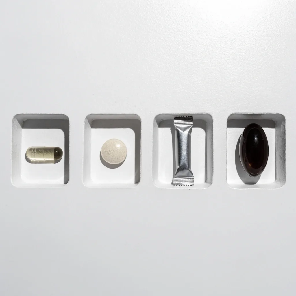 A capsule, tablet, sachet and softgel each placed in its own well on a white surface