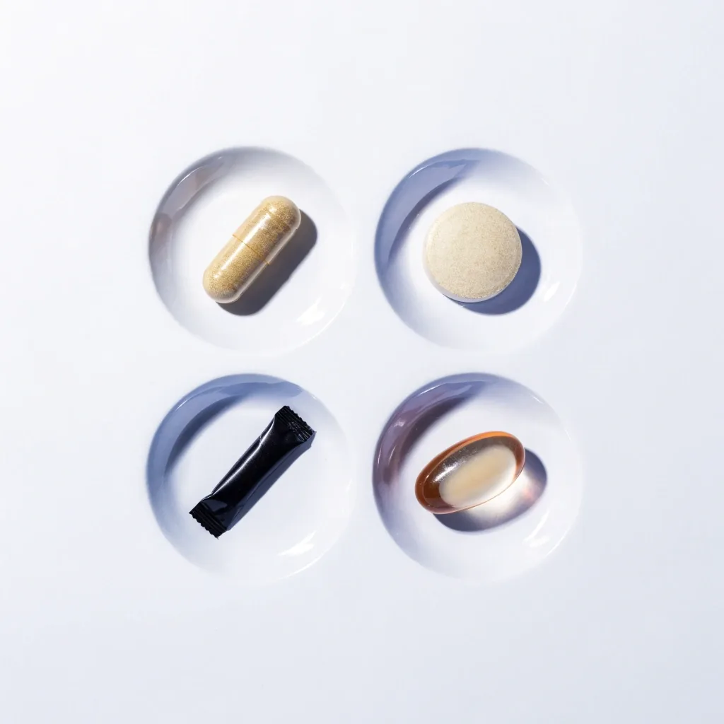 Four supplement formats laid singly inside shallow white wells on a matte surface